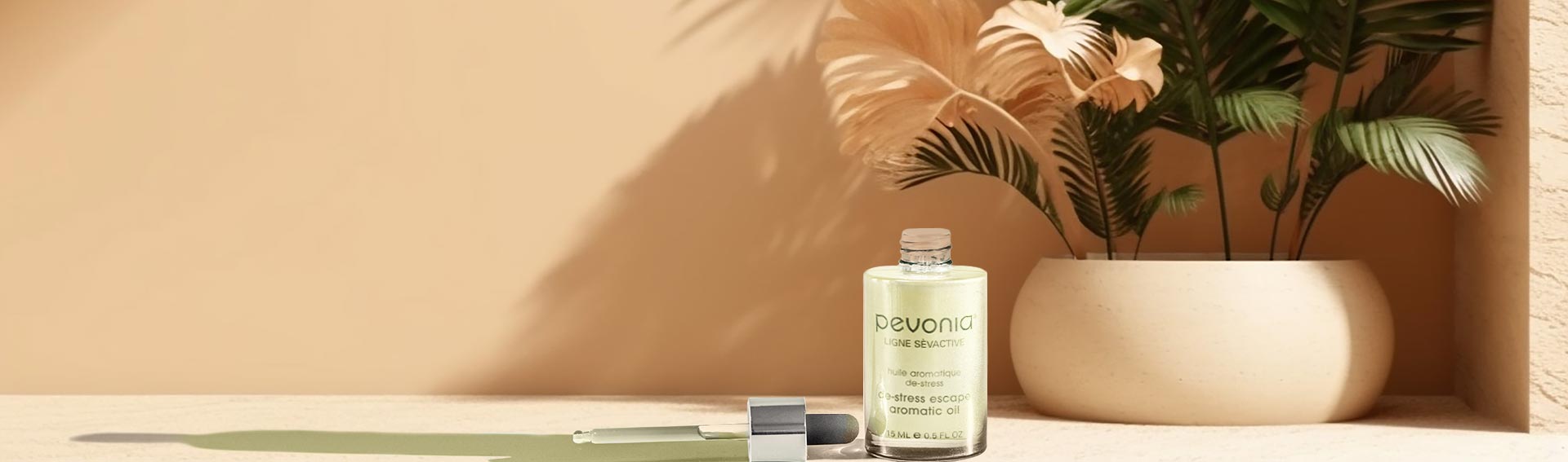 Pevonia's De-Stress Escape Aromatic Oil near a potted plant in the sun.