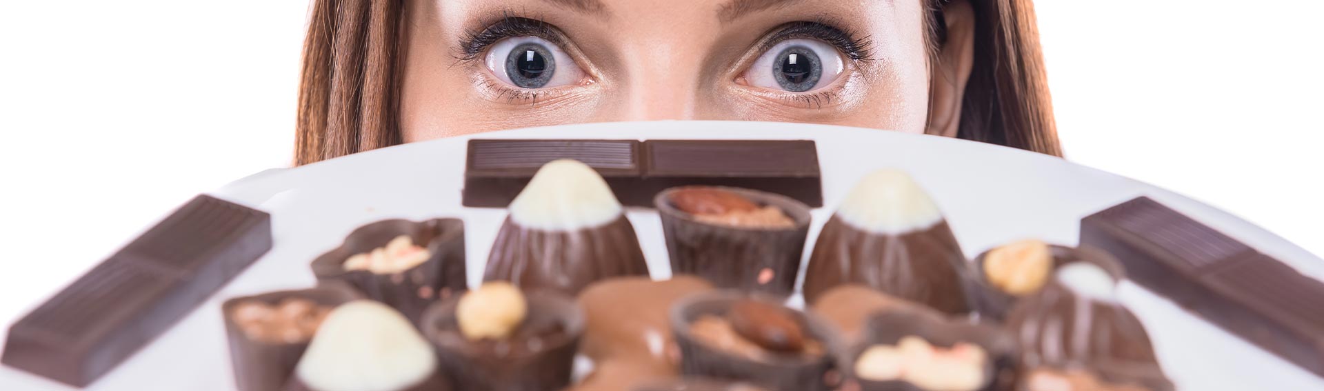 Woman peering over a plate of chocolates.