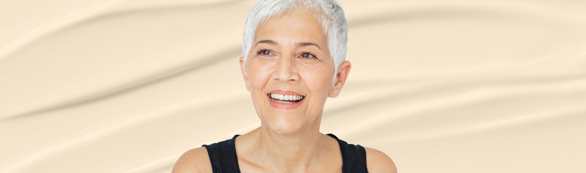 A woman smiling in front of a skincare cream texture.