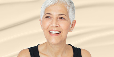 A woman smiling in front of a skincare cream texture.